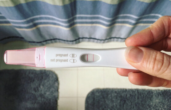 Hand holding positive pregnancy test