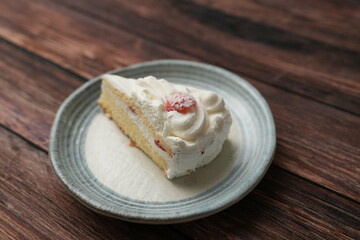 One small Japanese strawberry shortcake on a stylish Japanese plate on a brown wooden deck
