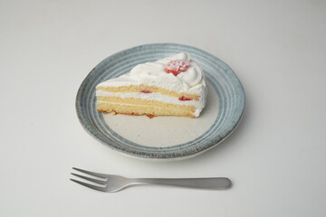 One small Japanese strawberry shortcake and a small fork on a stylish Japanese plate on a white table