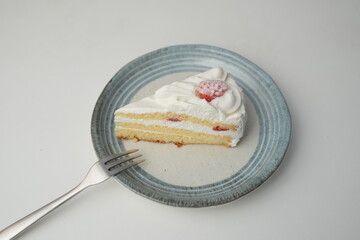 One small Japanese strawberry shortcake and a small fork on a stylish Japanese plate on a white table