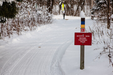 Caution sign informing cross-country skiers of the road ahead; Remove Skis Before Crossing Road