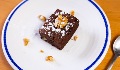 Piece of delicious brawny with walnuts served in a ceramic plate with teaspoon on the table