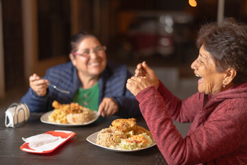 Two senior women enjoying fried chicken and rice at a street food stand