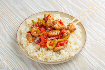 Delicious chicken stir fry with colorful bell peppers and fluffy rice, served on a plate with chopsticks, flavorful asian inspired dish