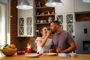 Young couple shares tender moment in morning kitchen, preparing fresh ingredients for their breakfast together.