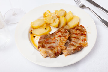 Fried juicy pork with boiled potatoes served on a plate