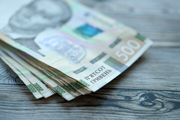 Many five hundred hryvnia money bills lies on wooden background. Ukrainian national currency close up