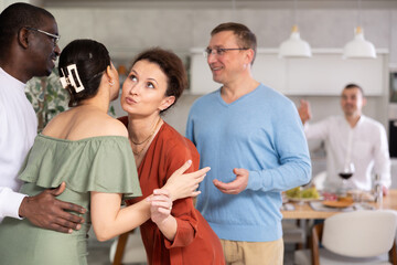 Multicultural female and male friends greeting each other when meeting in kitchen