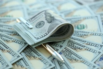 Golden pen clipping big amount of hundred dollar bills US banknotes