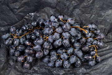 fresh grapes are lying on black paper