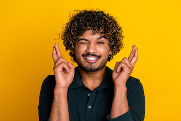 Young mixed race man with fingers crossed on yellow background hopes for good luck