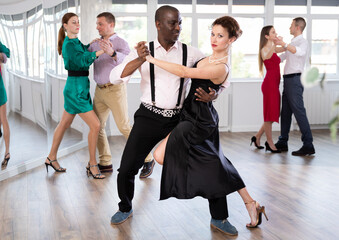 Active middle-aged lady training waltz in pair with man in dance-hall during dancing classes
