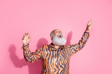 Portrait of funky aged man dancing tiger print shirt isolated on pink color background