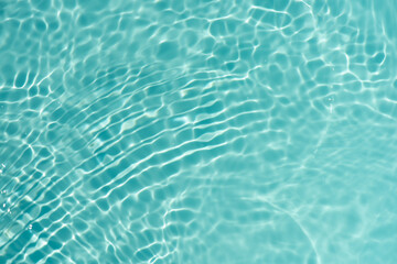 Blue water with ripples on the surface. Defocus blurred transparent blue colored clear calm water surface texture with splashes and bubbles. Water waves with shining pattern texture background.