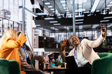 Powerful ambitious entrepreneurs take selfies together and having fun, making silly faces in photographs after finishing a business meeting. Diverse team of leaders with equal rights, funny photos.