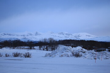 Winter landscapes in Norway showcase serene snowy mountains, icy fjords, and peaceful coastal views. Capturing the beauty of snow-covered trees, quiet roads, and glowing sunsets creates a sense of cal