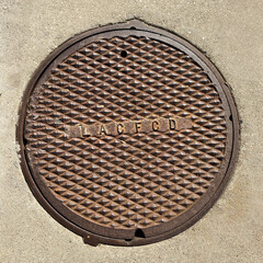 Manhole cover on cement sidewalk