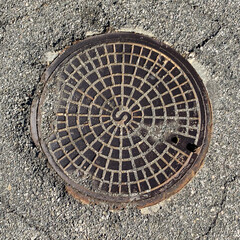 Manhole cover  in street surrounded by asphalt