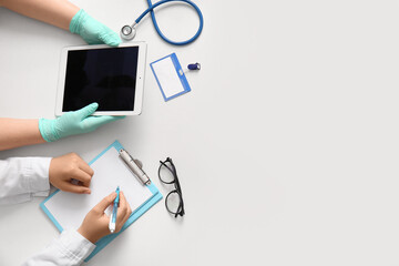 Doctor's hands with tablet, stethoscope and clipboard on white background