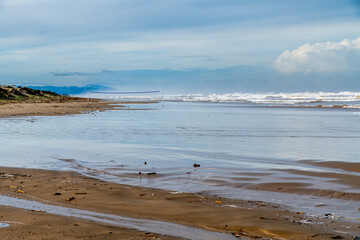 Lonely Volleyball Net on Wet Beach with Reflection and Distant Hills