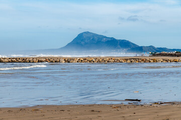 Wide Sandy Beach with Calm Water, Mountain and Coastal Buildings