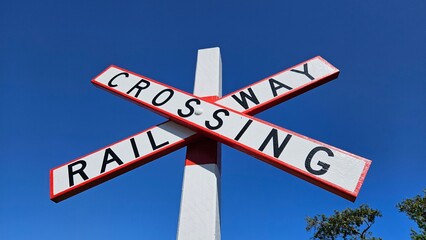 Fototapeta premium Red and white railway crossing sign against clear blue sky
