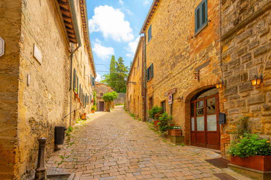 A cobblestone alley in the historic medieval center of the Italian hill town of Volterra, Italy, in the Tuscany region. - Powered by Adobe