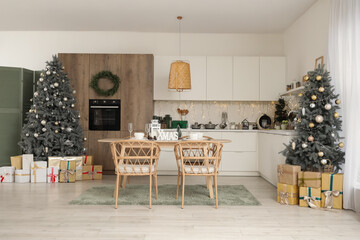 Interior of kitchen with Christmas trees, dining table and glowing lights
