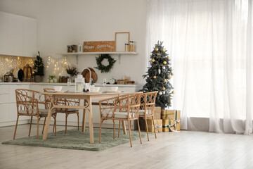 Interior of kitchen with Christmas trees, dining table and glowing lights