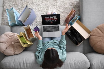 Young woman with credit card and laptop with text BLACK FRIDAY SALE at home