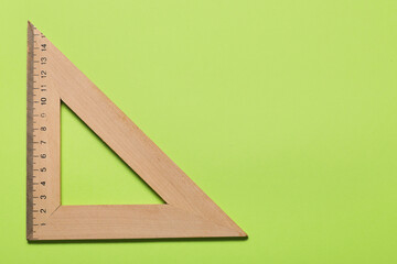 Wooden triangle ruler on green background