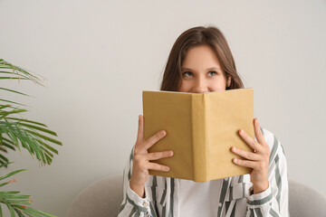 Dreamy young woman reading book at home