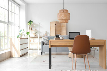 Interior of light living room with programmer's workplace, sofa and drawers