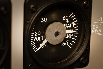 Needles and dials and gauges. A vintage Voltmeter in an old aircraft cockpit tells the status of the airplane battery and its remaining charge. An essential component for the safety of aviation 