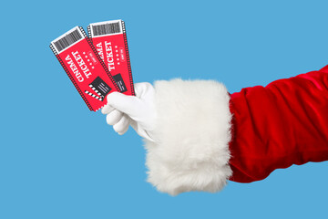 Santa's hand with cinema tickets on blue background