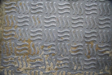 Close-up photo of a grey surface with a repeating wavy pattern. Wavy Pattern on Grey Surface Tile Background concept.