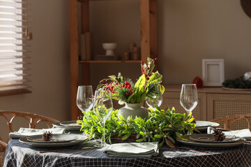 Beautiful table setting with mistletoe wreath and Christmas tree branches in living room, closeup