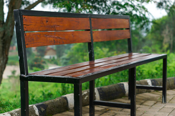 Naklejka premium Wooden bench in a serene outdoor setting surrounded by lush greenery.