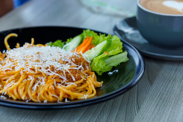 A delicious plate of pasta topped with grated cheese and fresh vegetables on the side.