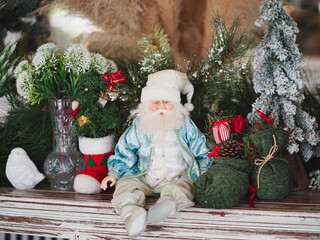 Merry Christmas. A Santa Claus in vintage white and pastel blue professional Santa suits is sitting among the Christmas decoration. Display set up for Christmas and Happy New Year festival.