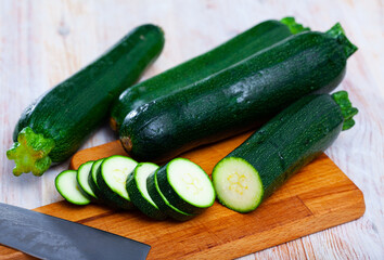 Image of cut raw green zucchini on wooden surface in kitchen