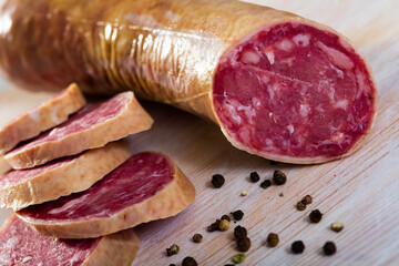 View of smoked salchichon sausage and slices on wooden background