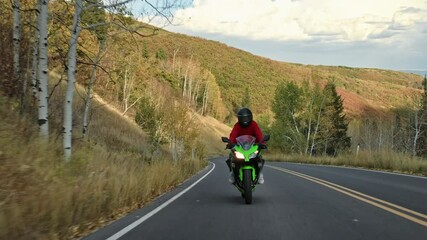 Green motorcycle speeding down canyon road at sunset - front