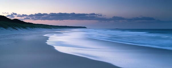Fototapeta premium A serene beach at twilight, with gentle waves lapping against the shore.