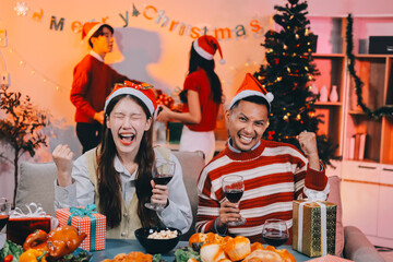 Group of happy Asian friends celebrating Christmas and decorate the Christmas tree indoors. Beauty woman with Christmas Gifts. New Year party. Woman hands decorate Christmas tree red ball, bauble.