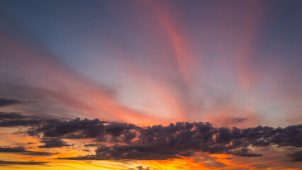 Fototapeta premium Sunset background. Dramatic majestic scenery sunset. Sky with clouds in sunset sky light background. Sunrise with clouds in various shapes. Calm sunset sky and sun through clouds over.