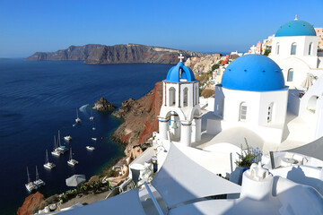 Oia Santorini's iconic blue-domed churches overlooking the island's volcanic caldera and the Mediterranean Sea	