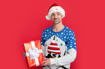 man with present from xmas sale in studio. cheerful caucasian man hold xmas present isolated on red.