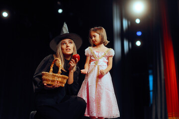 Evil Witch Showing Poisoned Apple to a Little Snow White. Team of actors in a kids play performing...