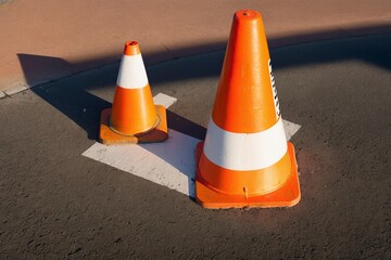 Orange traffic cones on asphalt road with large hole on background, symbolizing caution and safety in construction area